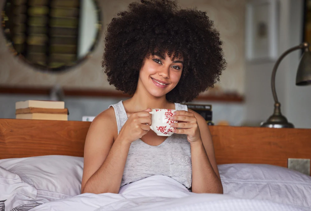 Calm woman relaxing in bed with mug